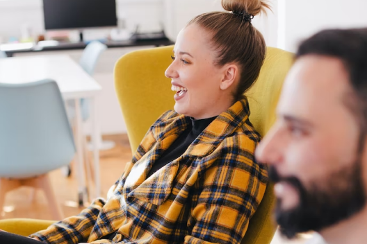 Two smiling coworkers watching something out of frame.